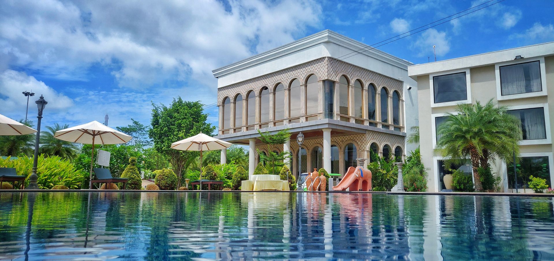 The resort's outdoor pool with the building and palms behind